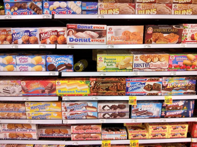 Supermarket shelf with packaged foods and nutrition labels being checked